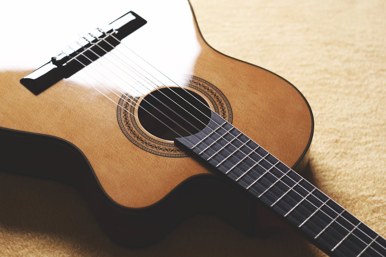 about-01 A beautifully crafted acoustic guitar showing its wooden body and strings in close detail.